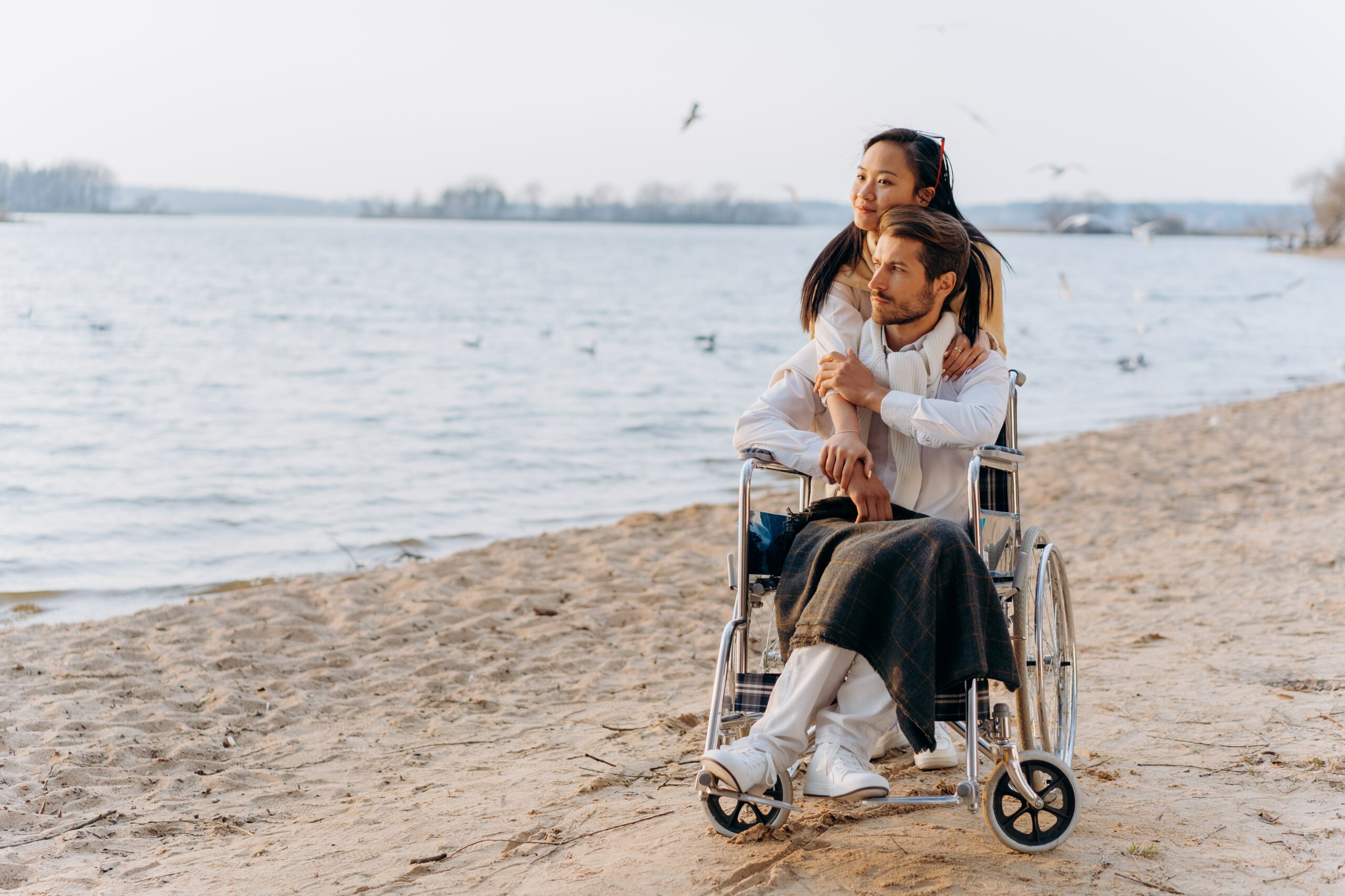 A couple, one in a wheelchair, on the beach