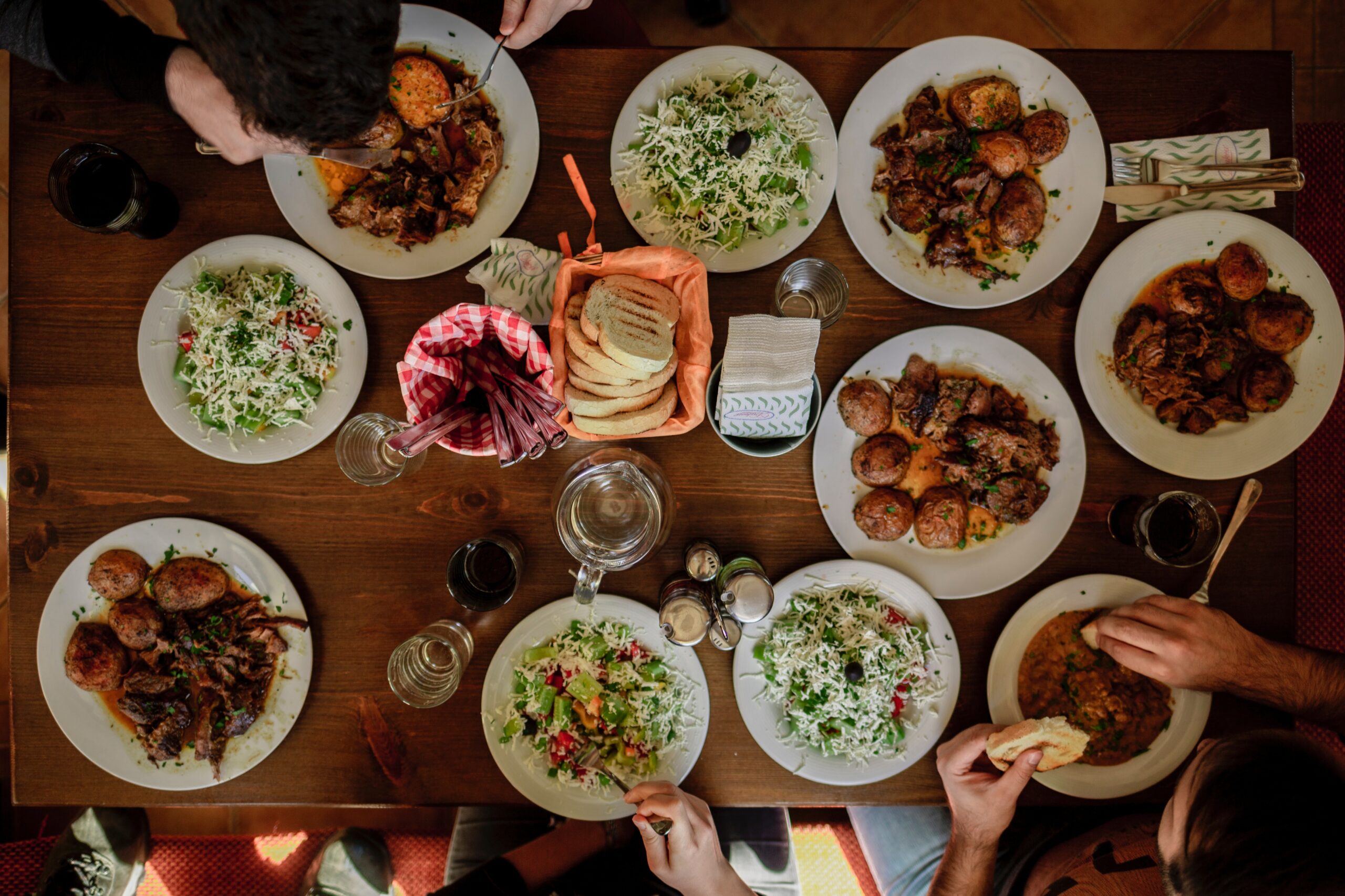 This is a photo from above a dinner table. The table has many large plates, filled with food.