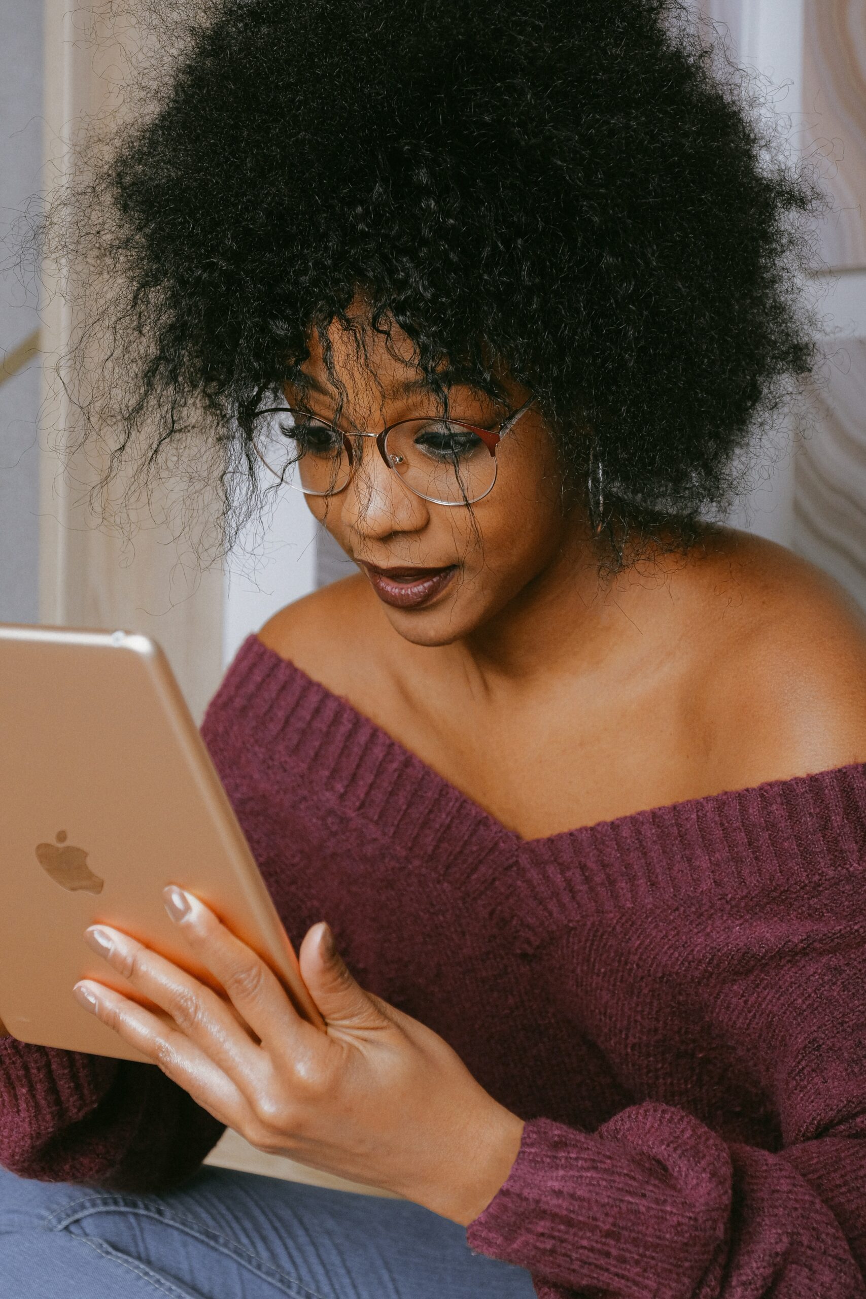 Woman wearing an off-the-shoulder purple sweater looking at an iPad