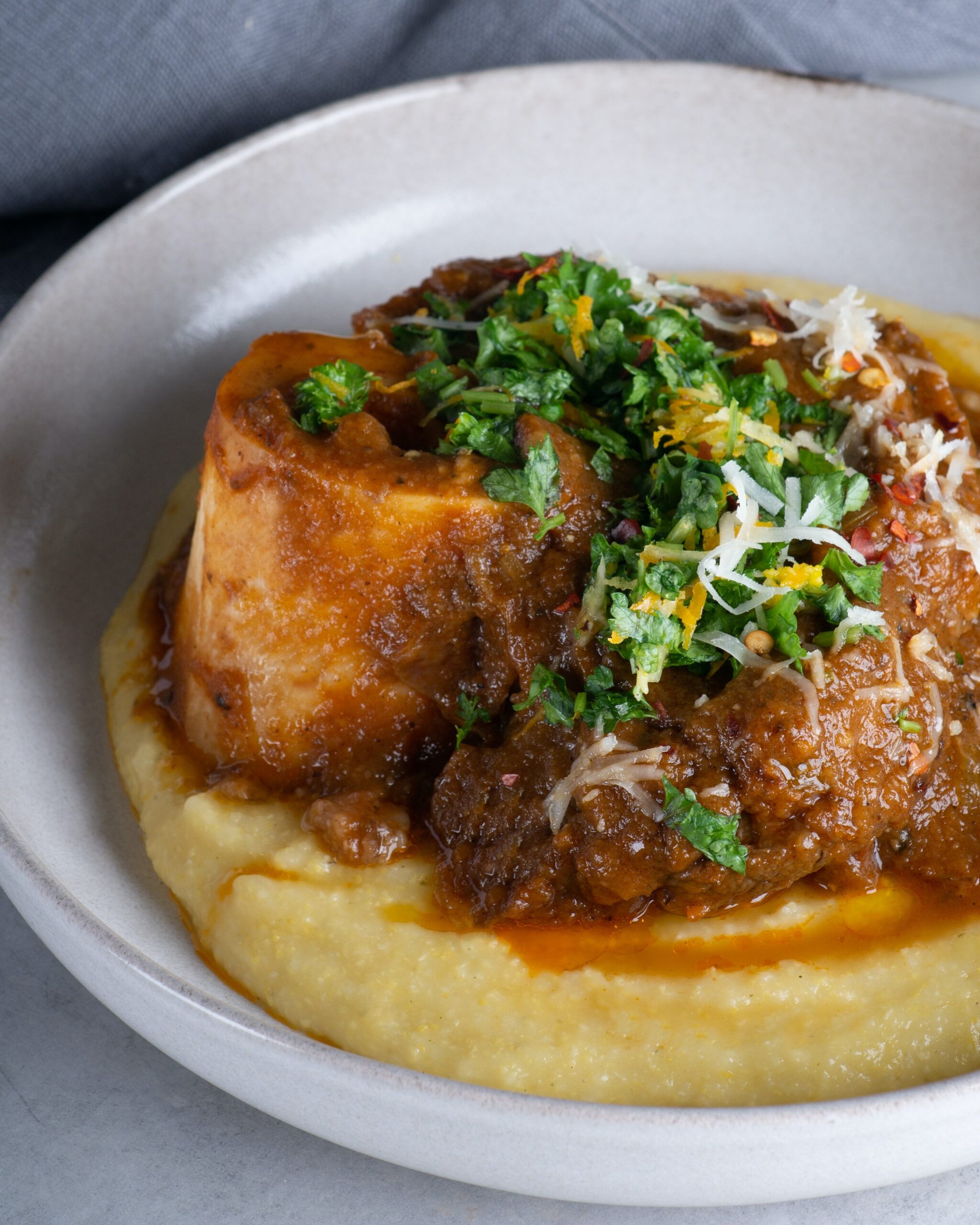 Polenta garnished with greens on a white plate.