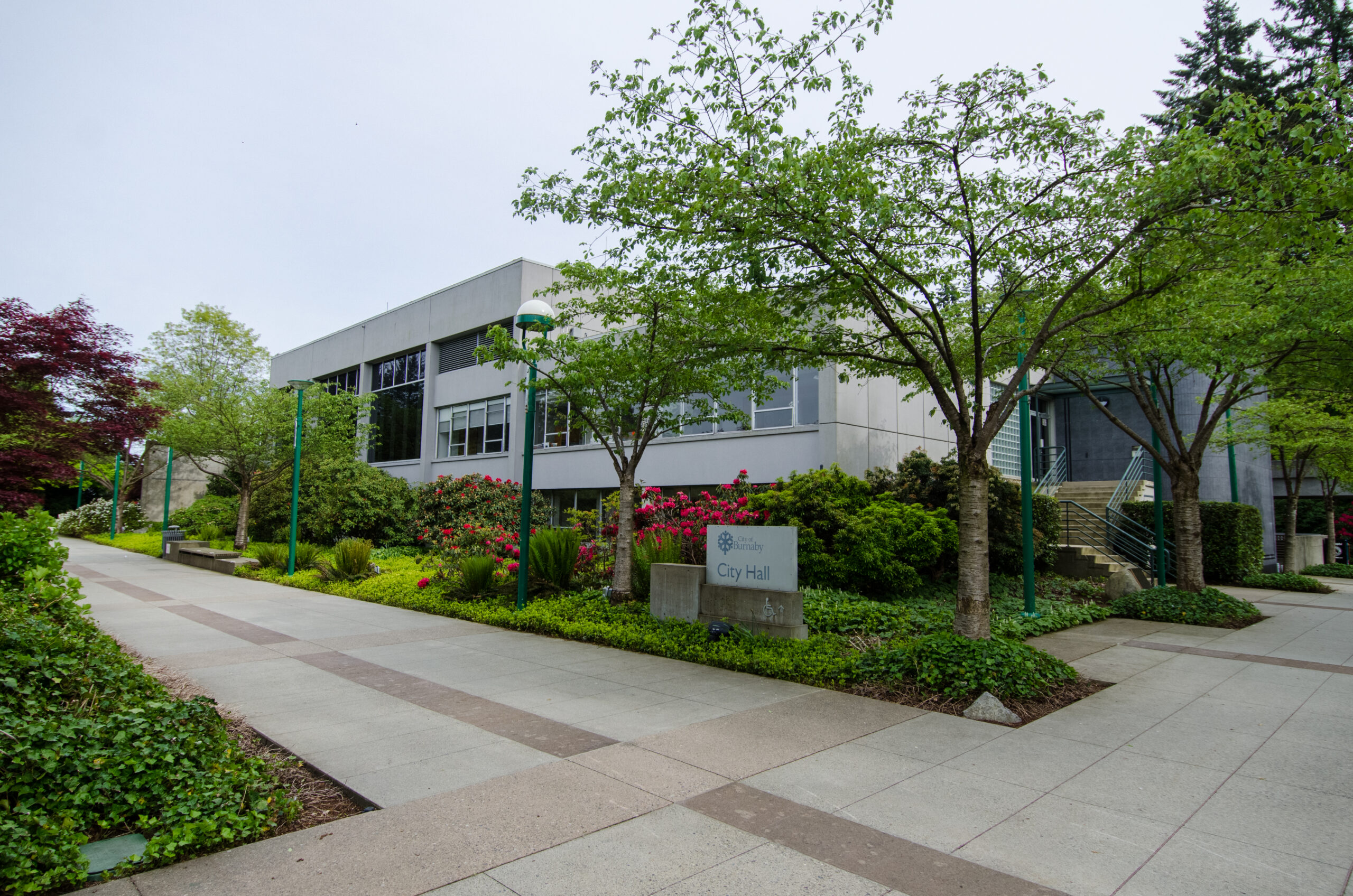 This is a photo of the outside of SFU Burnaby’s city hall. The building has a lot of plants and trees around it.
