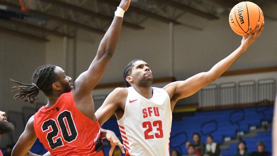 photo of an SFU player laying up the ball with an opponent guarding them.