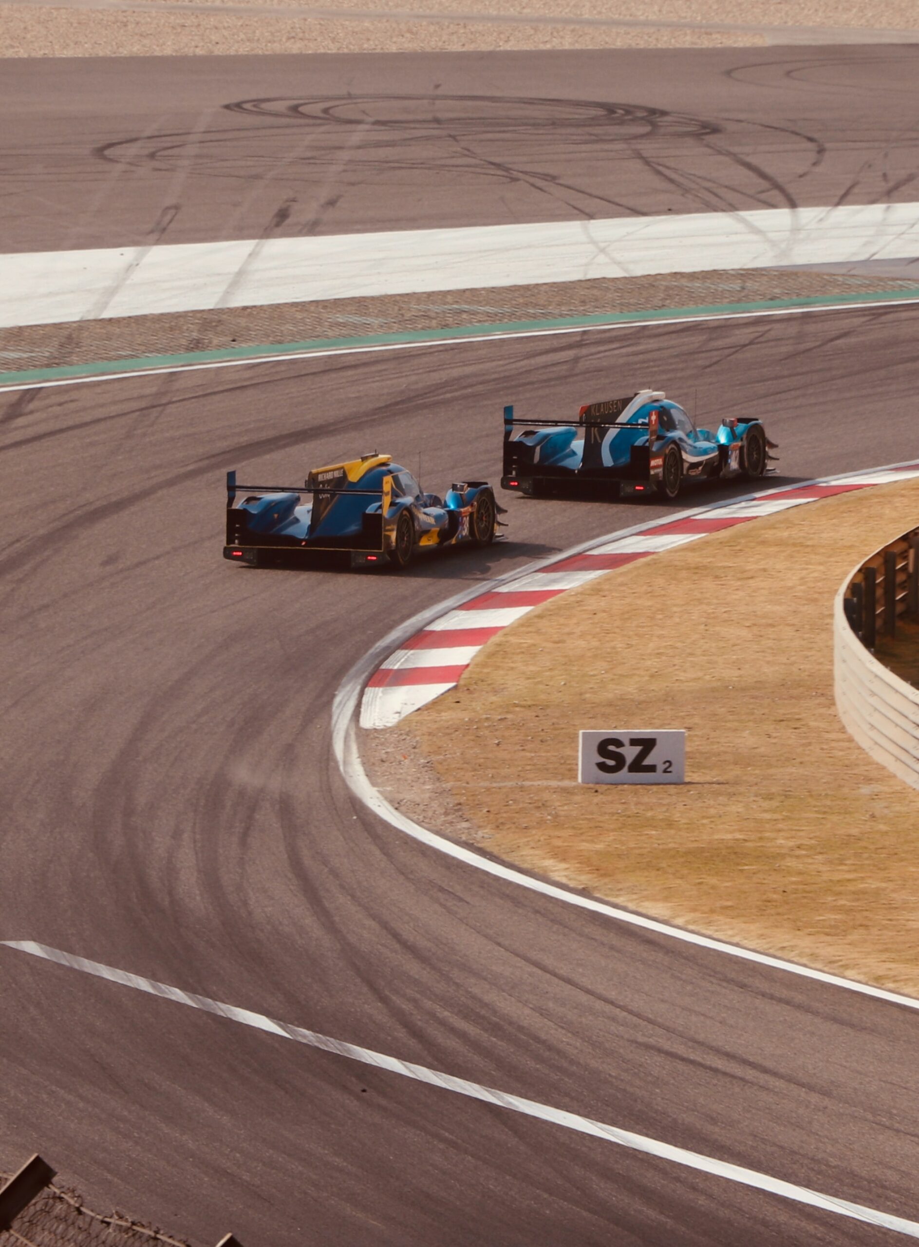photo of two F1 cars behind one another on the track turning the corner.