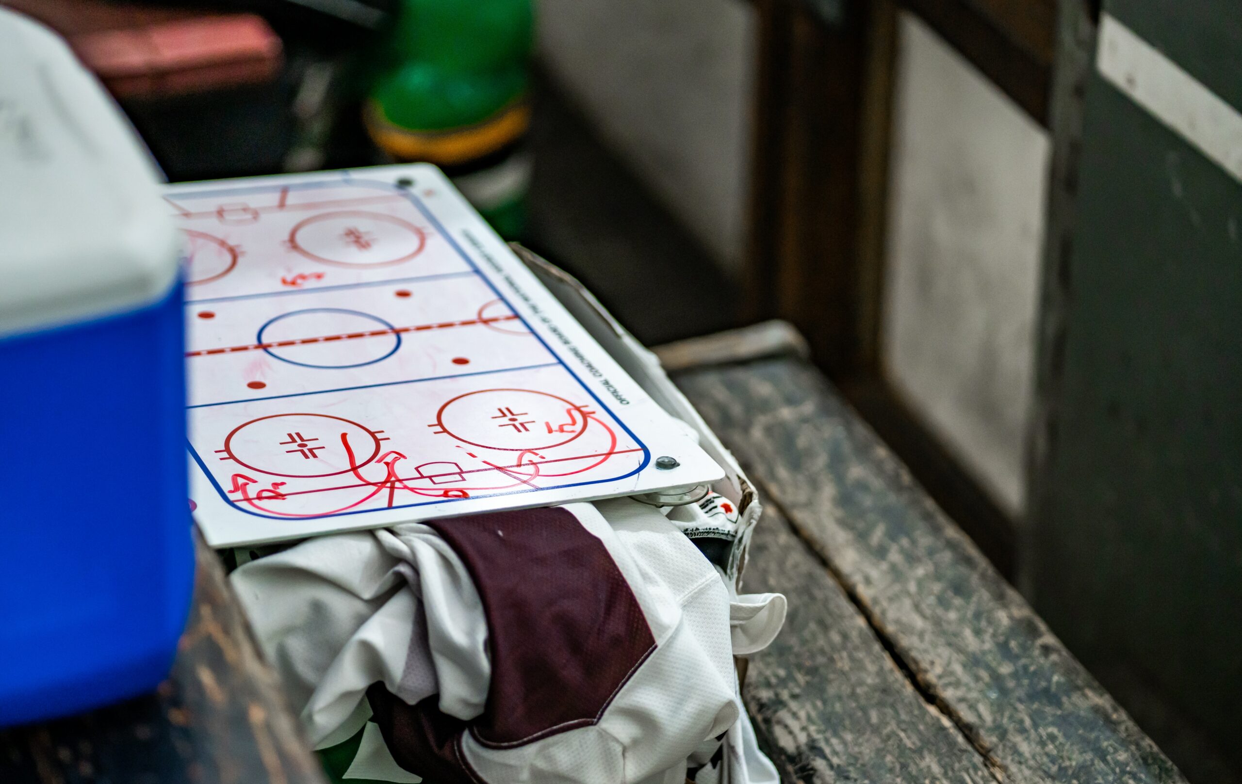 photo of a hockey clipboard laying on top of a jersey on the bench.