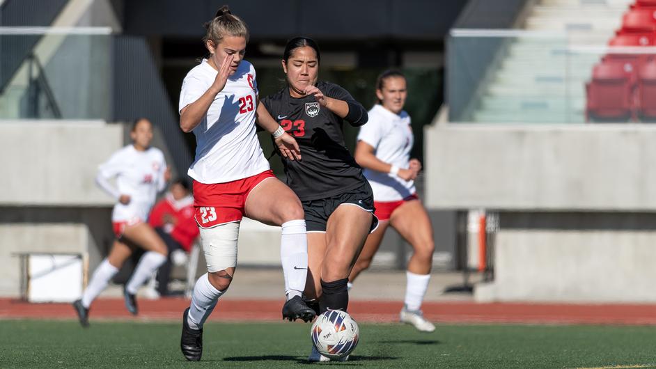 photo of an SFU soccer player fighting to keep possession of the ball against an opponent.