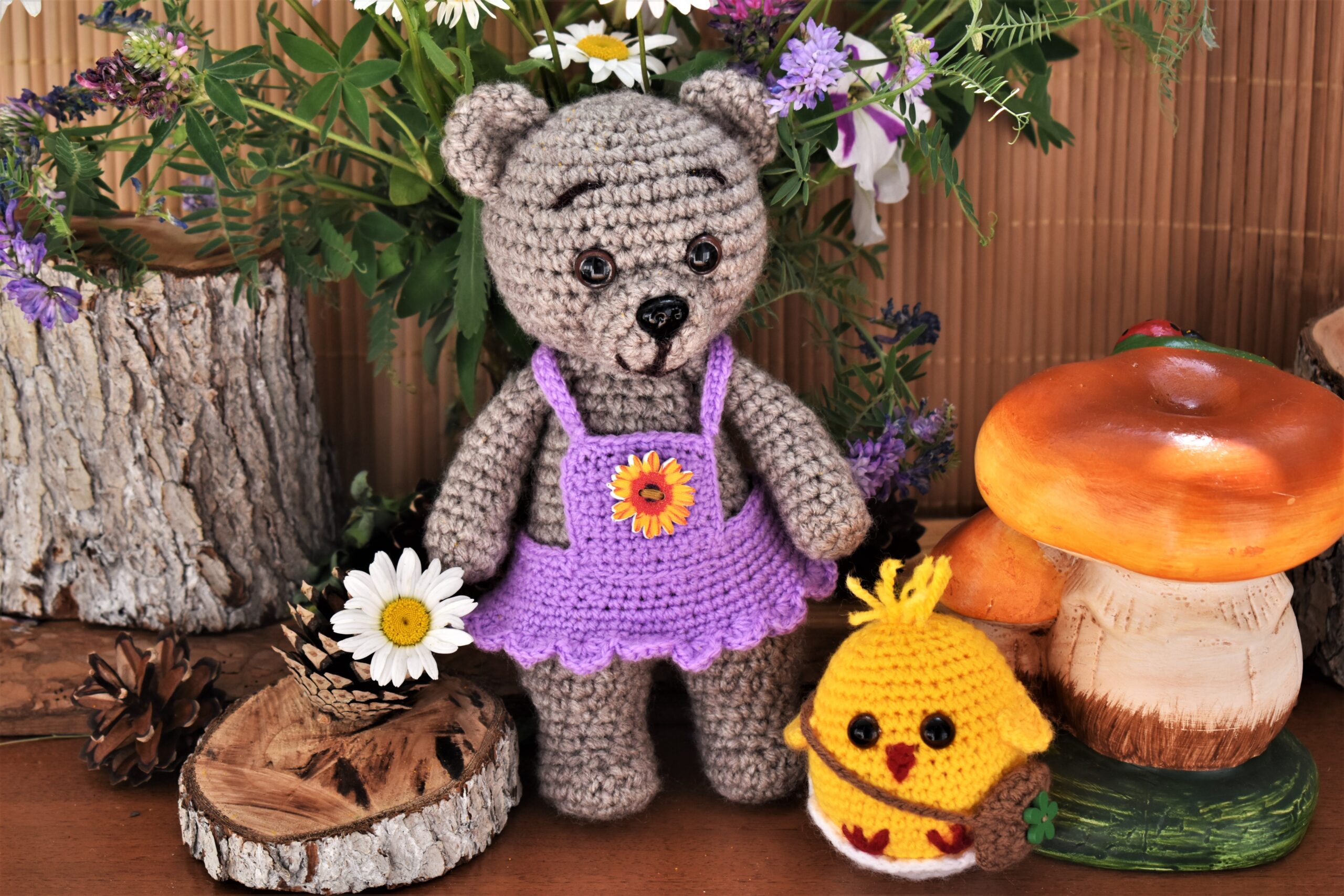 Stuffed crochet bear and chick surrounded by fake plants.