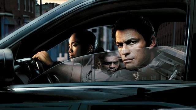 The Wire TV series cover featuring a man in a car with the window pulled down looking out the window with a scowl on his face. In the window reflection, a man is scowling back at him.