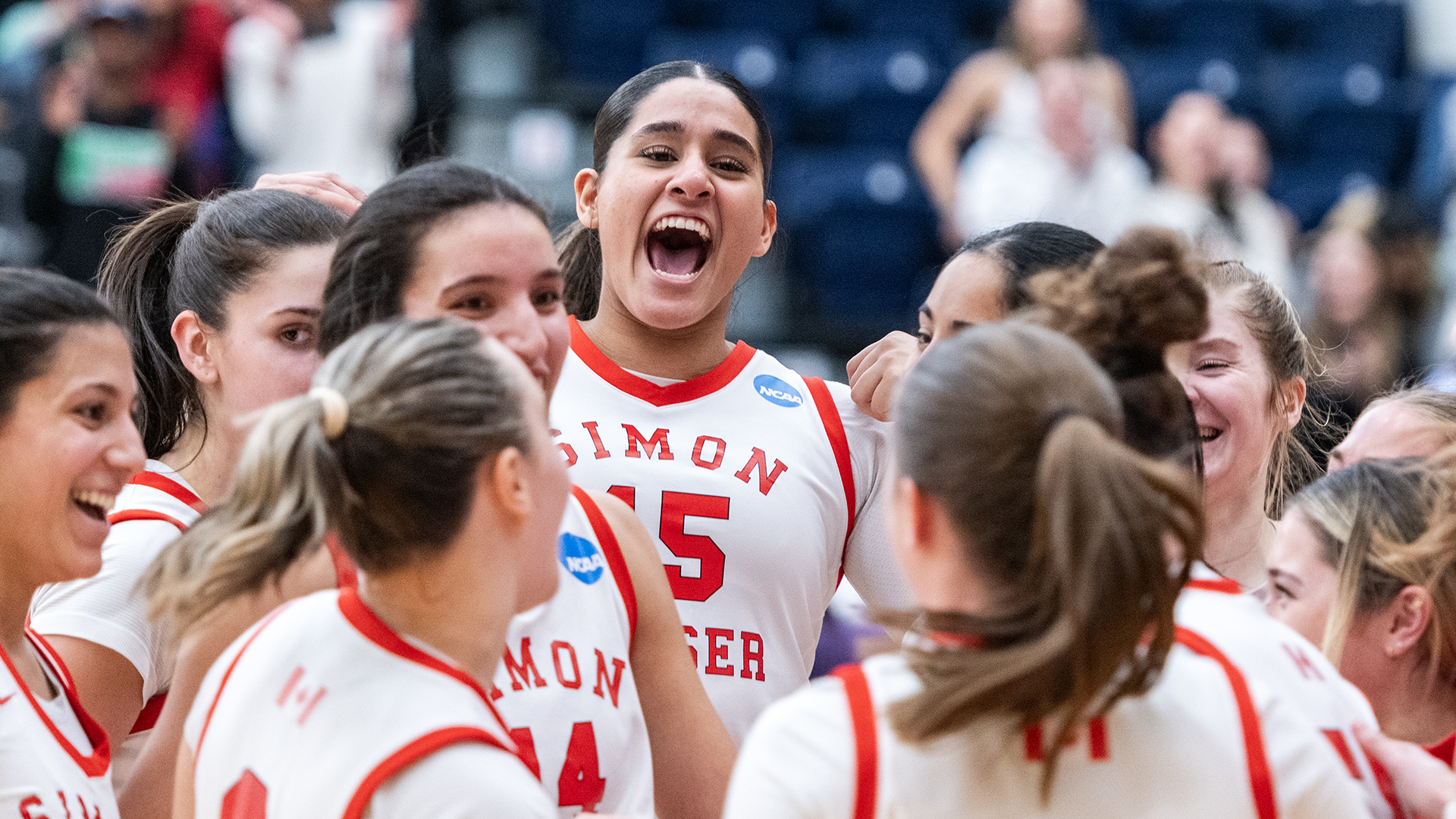 women’s basketball team celebrating in a team huddle