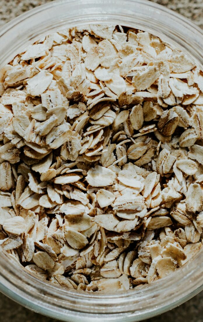 andrea-tummons-UFQQkXV-jwU-unsplash Close up of a clear plastic container filled with oats.