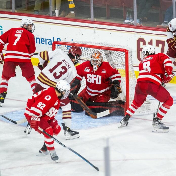 Boston College player at the front of the SFU net with SFU players surrounding him.