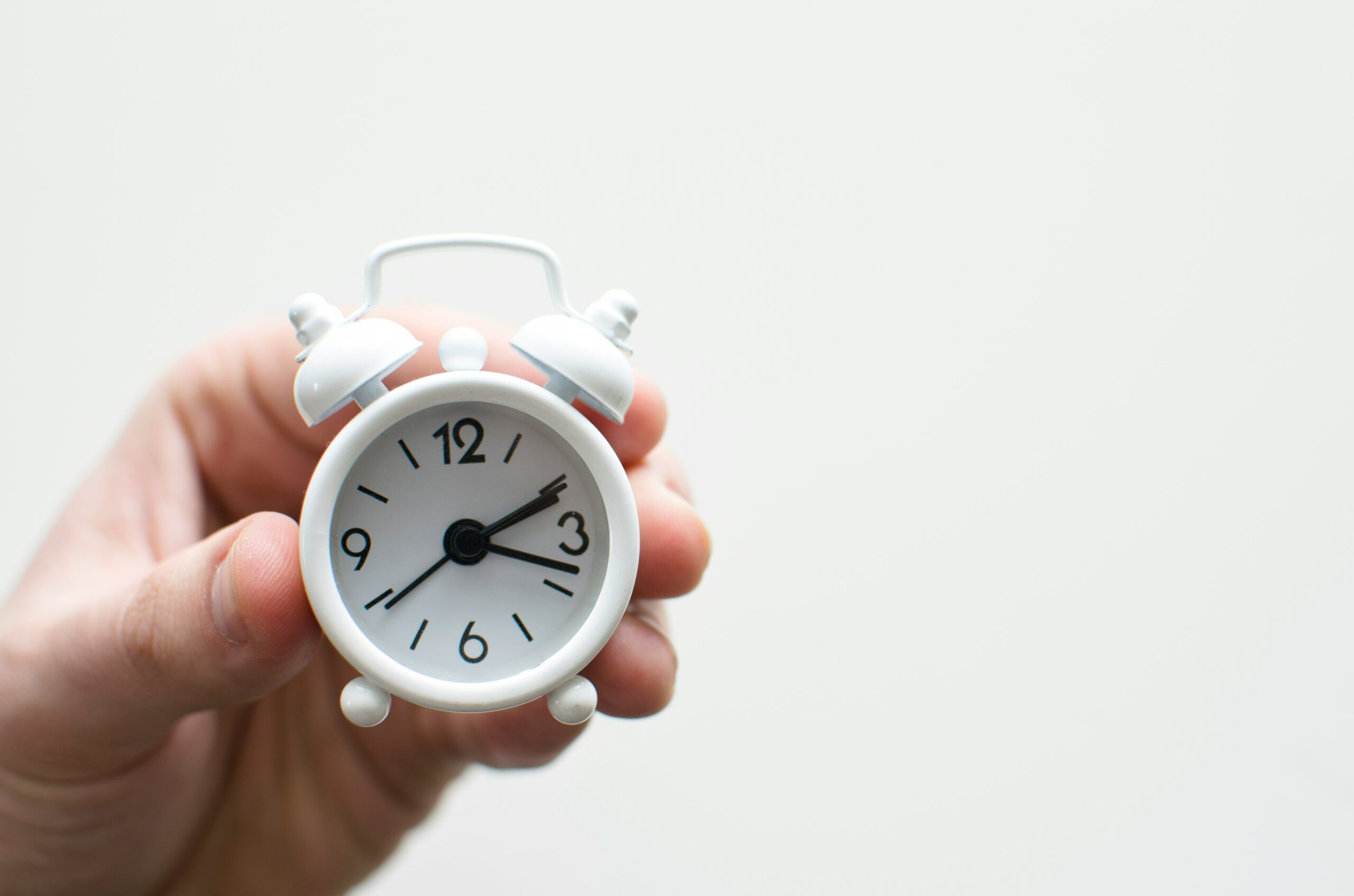 Person holding a tiny toy clock