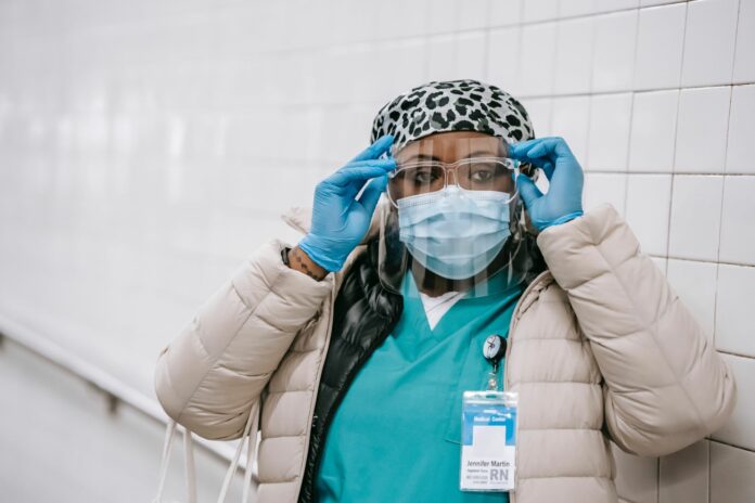 pexels-laura-james-60980055 A Black healthcare worker wearing a mask, gloves, and face shield