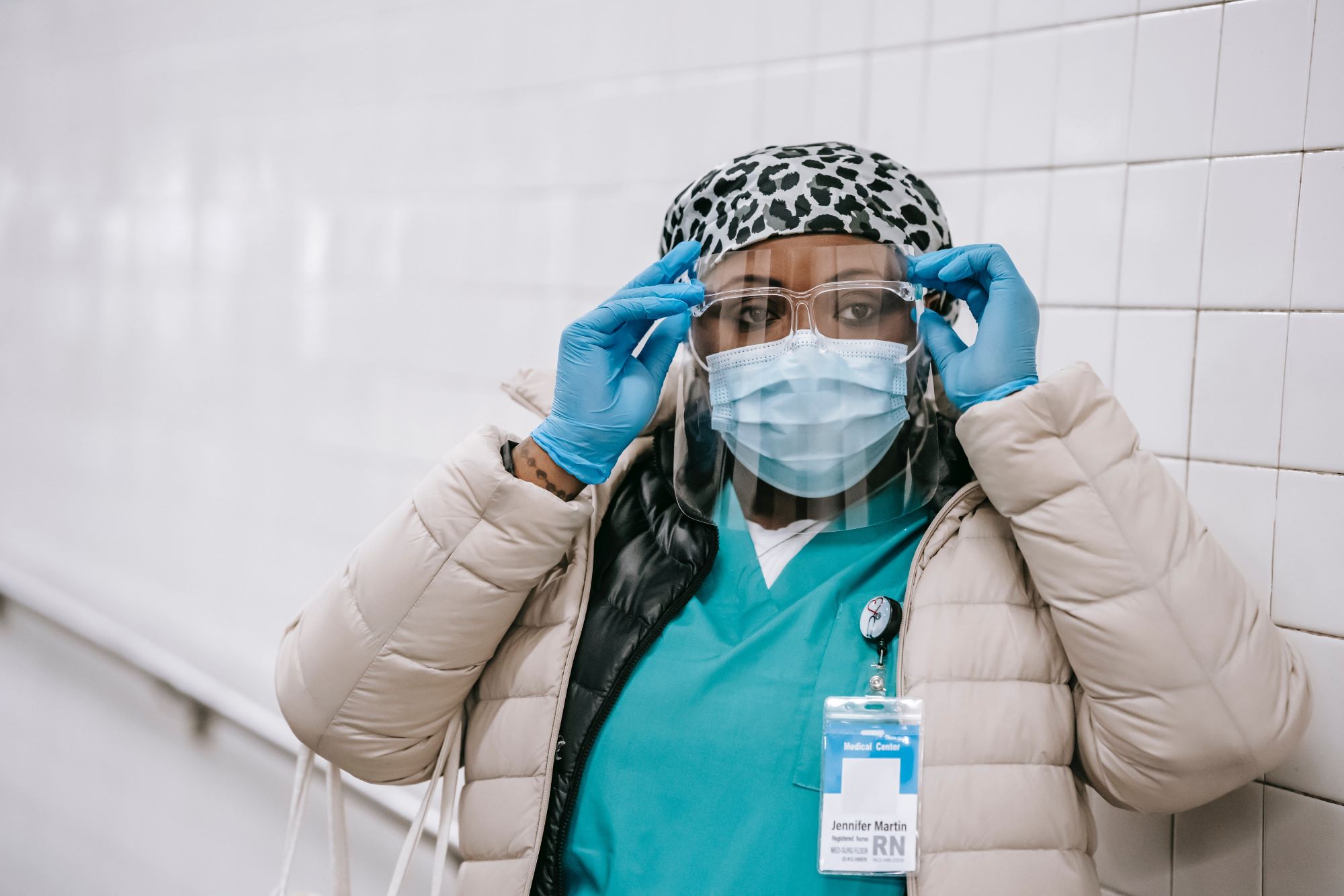 A Black healthcare worker wearing a mask, gloves, and face shield