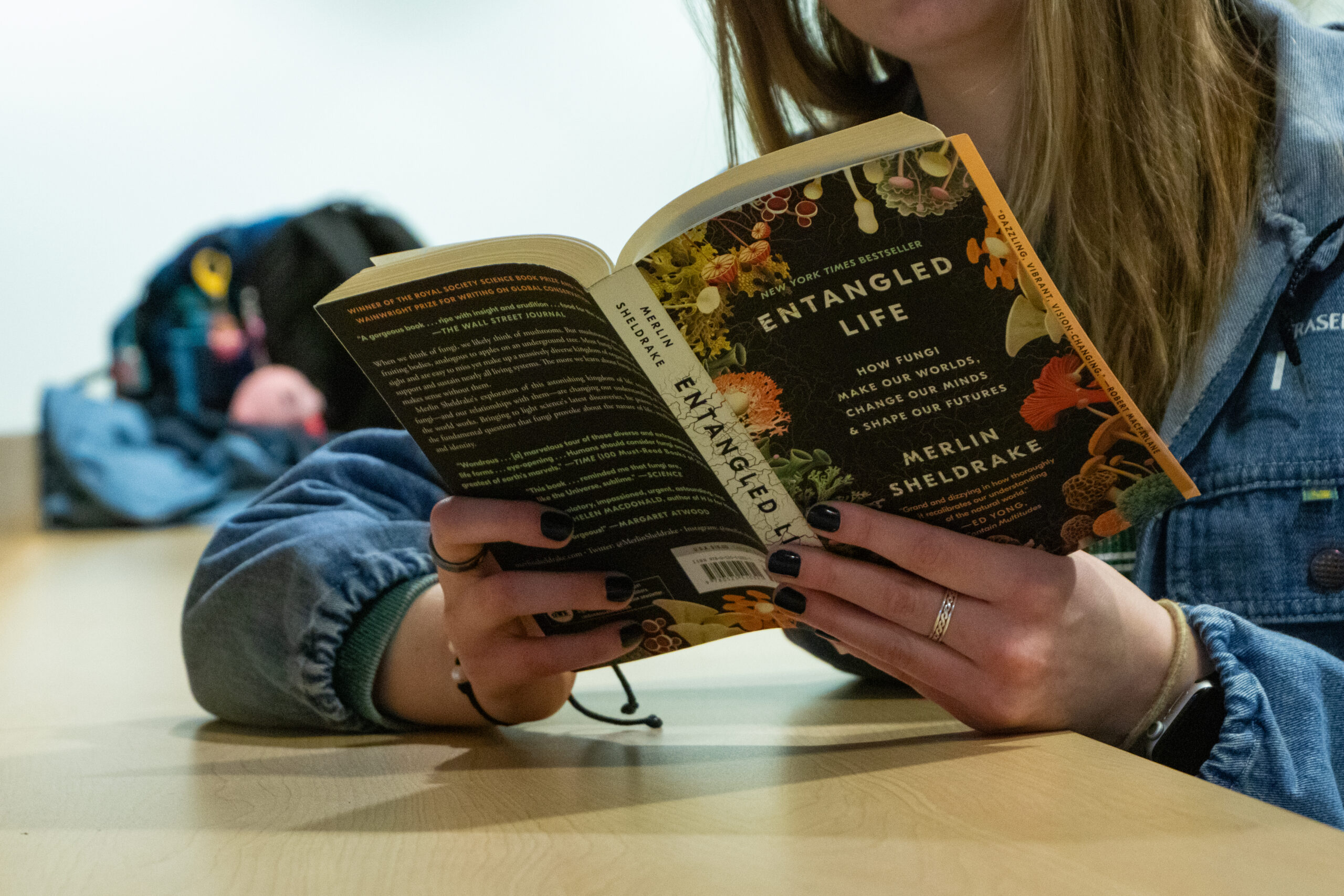 A person reading a book with the title Entangled Life