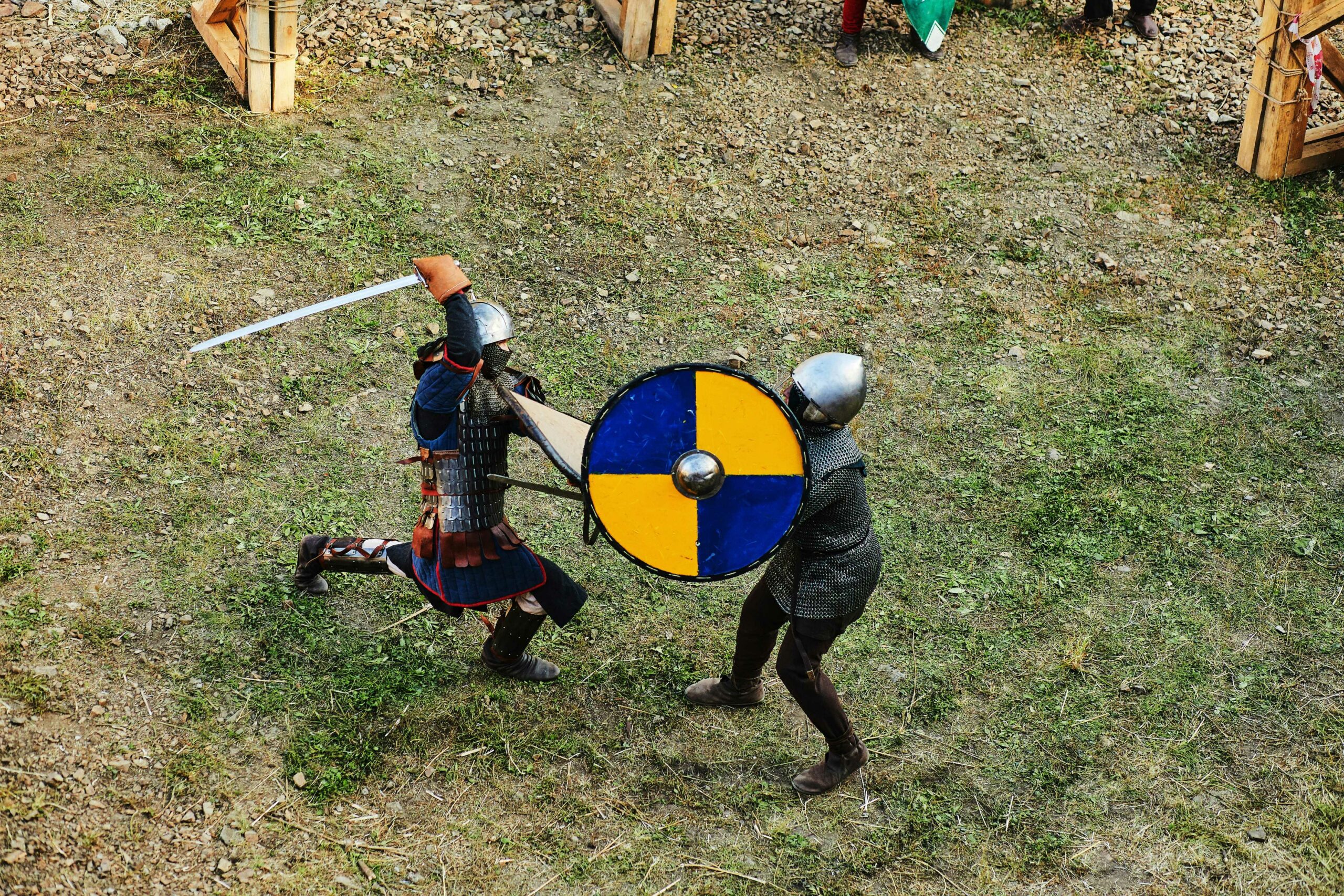 Photo of two people dressed up in medieval armour outside spearing with dull swords.