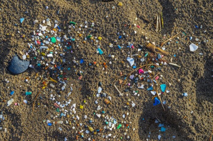 Micro plastics mixed in the sand of the beach This is a photo of sand that contains multiple pieces of small colourful plastics.