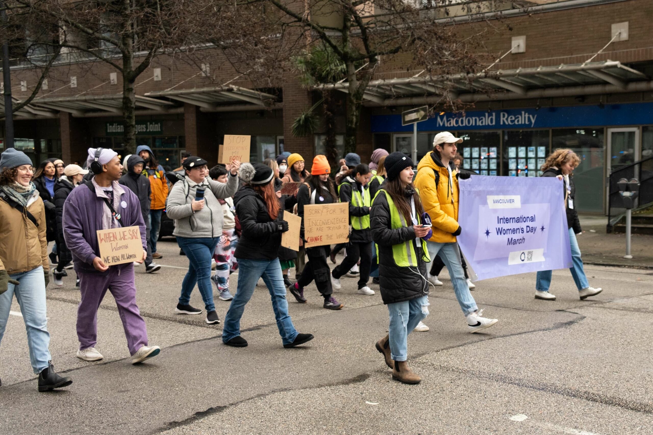 This is a photo of the rally participants, holding signs, walking down the middle of the street.