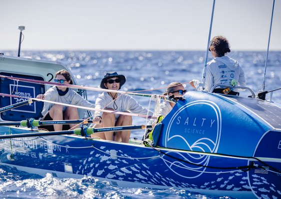 This is a photo of the rowing team in their boat. The four women are rowing.