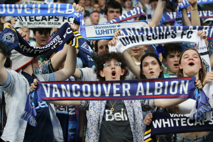 Vancouver Albion fans holding team scarves above their heads while watching the game
