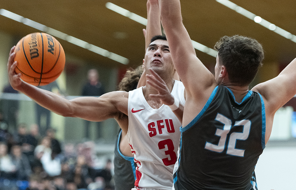 SFU men’s basketball player David Penney laying the ball in while being two-teamed