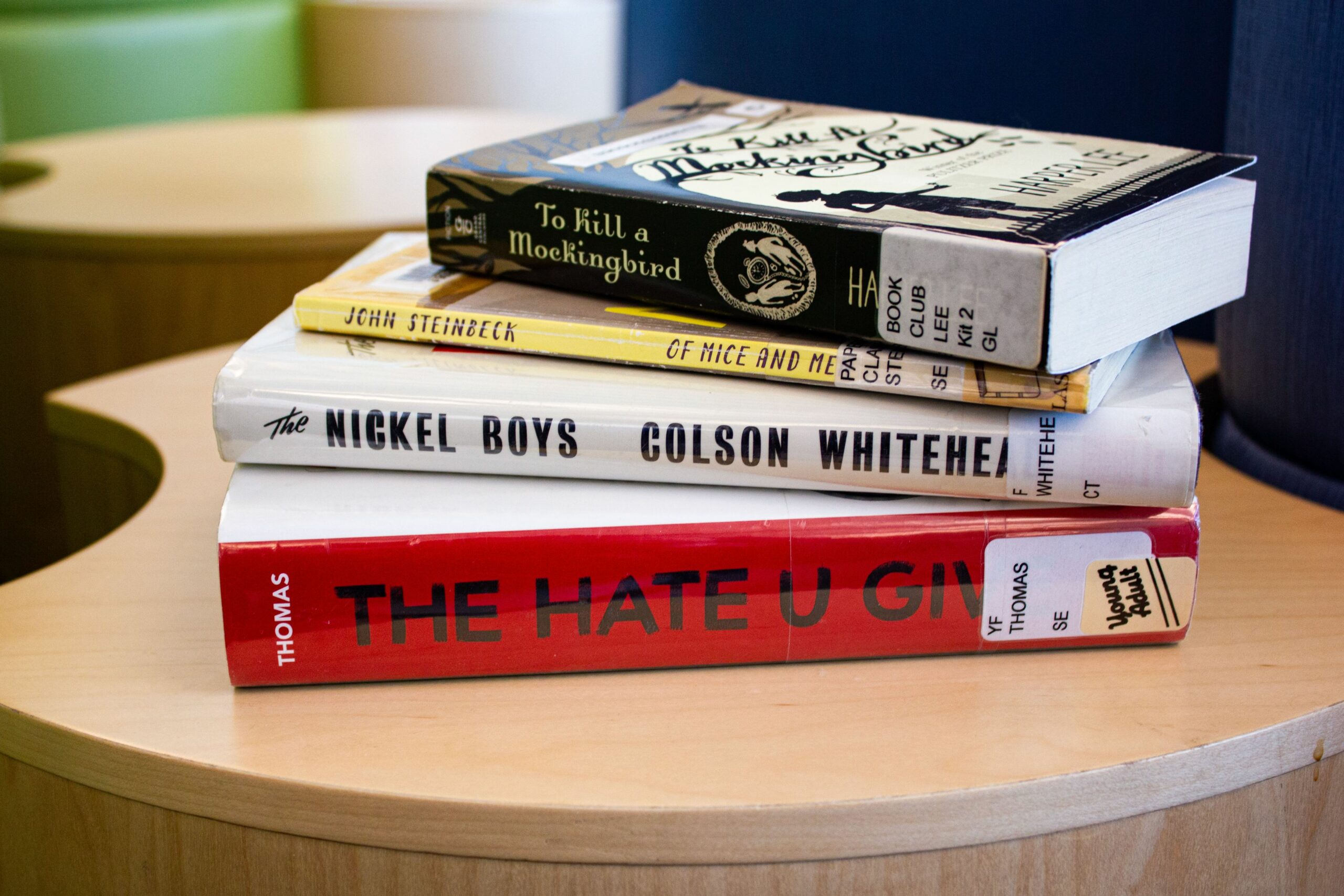 A stack of books, including To Kill a Mockingbird, The Hate U Give, Of Mice and Men, and The Nickel Boys
