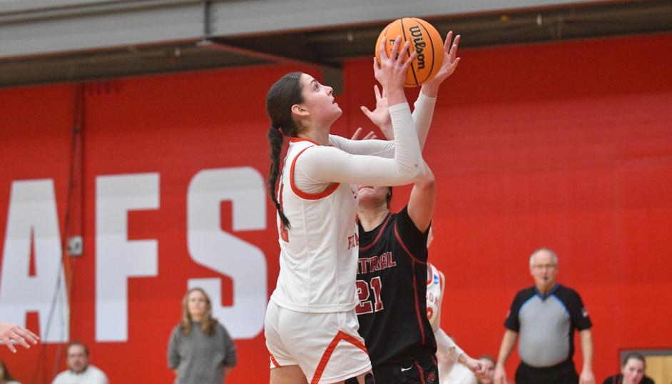 SFU women’s basketball player shooting the ball in while facing pressure from an opponent's block.