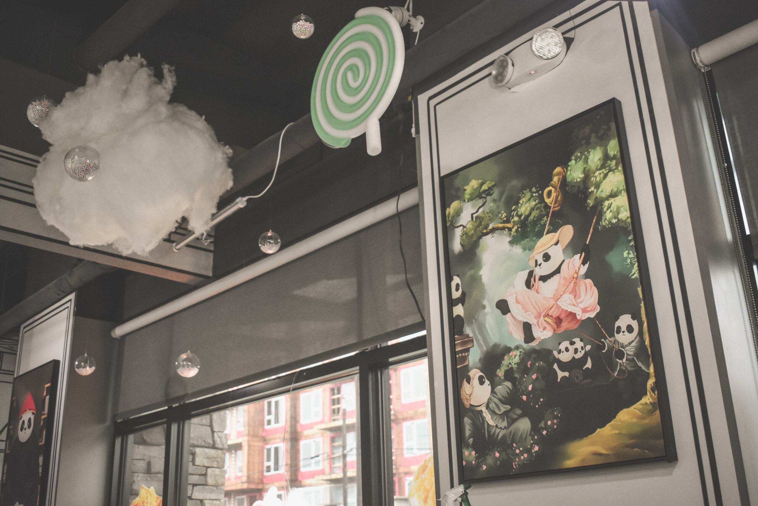 The interior of Something Sweet cafe featuring cotton cloud decorations and a sophisticated painting of a panda.