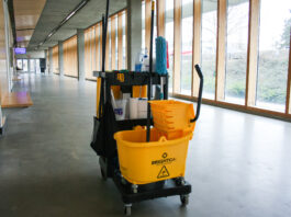 A rolling mop bucket with cleaning gear in a hallway of Blusson Hall