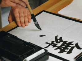 Chinese calligraphy being written with a thick brush in black ink.
