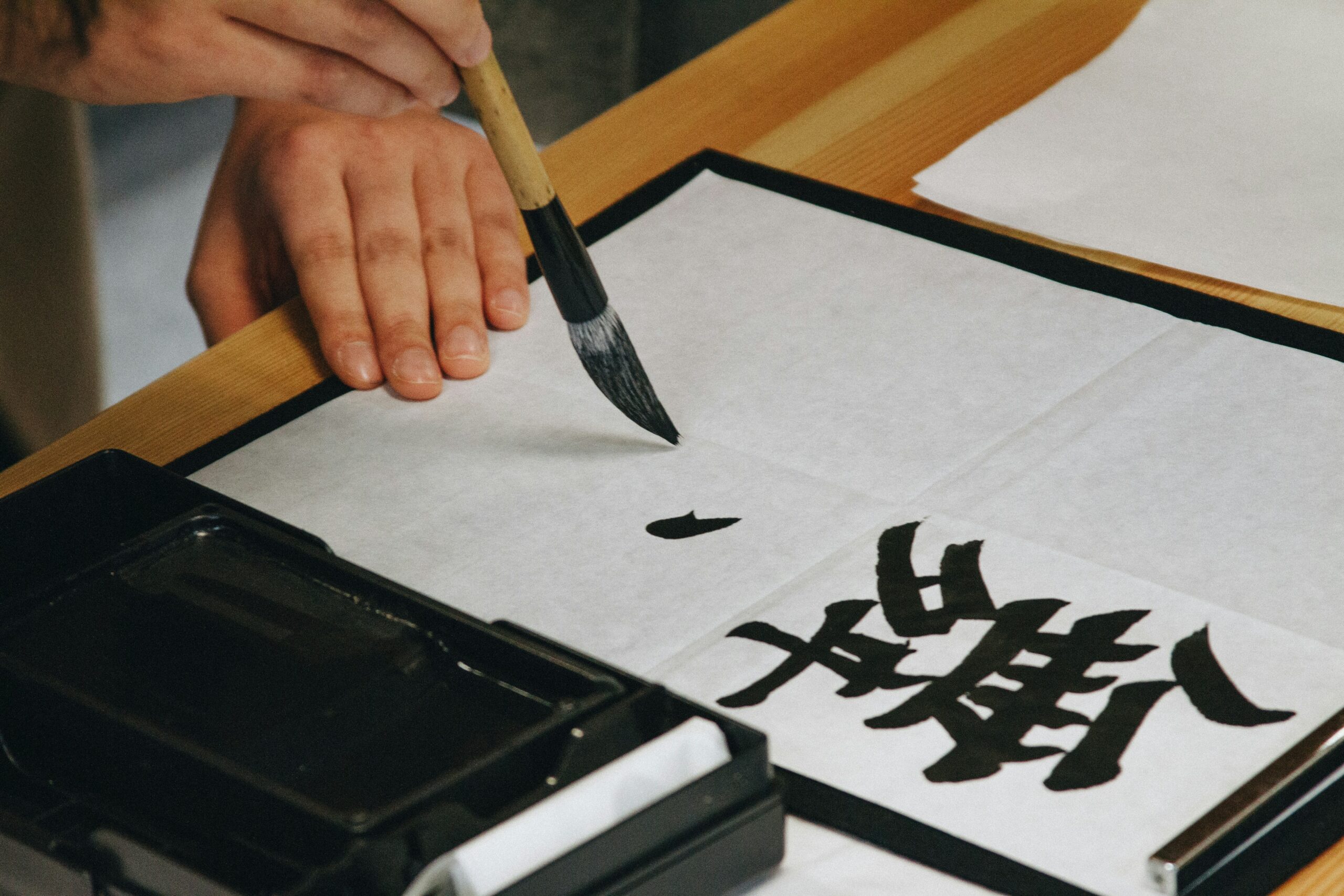 Chinese calligraphy being written with a thick brush in black ink.