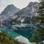 Peakie gets outdoorsy Mountains near a body of water. The reflection of the mountains is visible in the water.