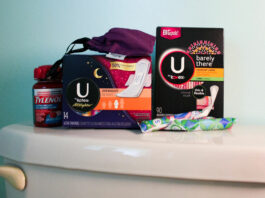 various period products, pads, and tampons stacked on a toilet lid