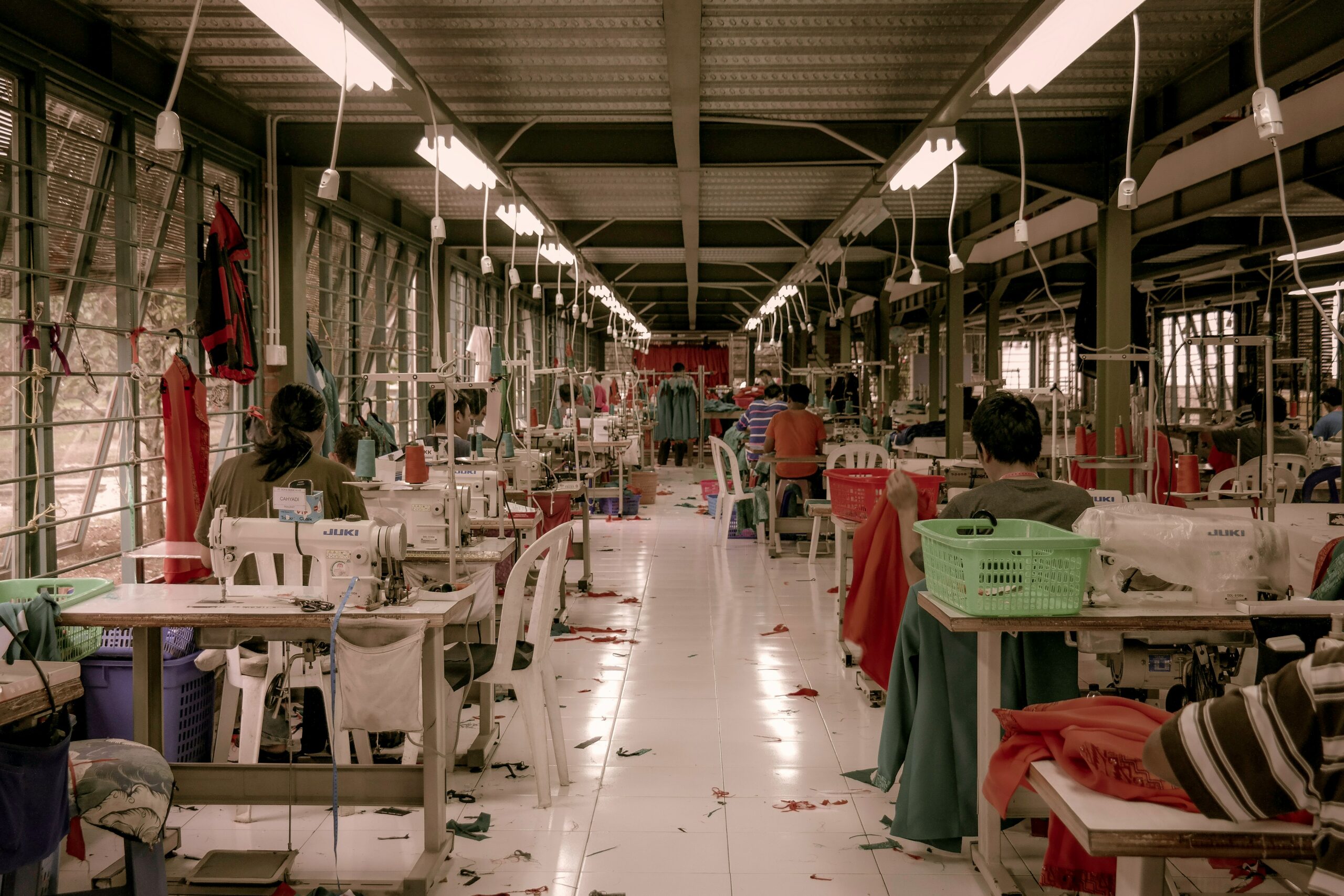 A small sweatshop filled with workers and fabrics.