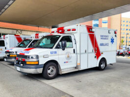 a row of three ambulances parked outside a hospital