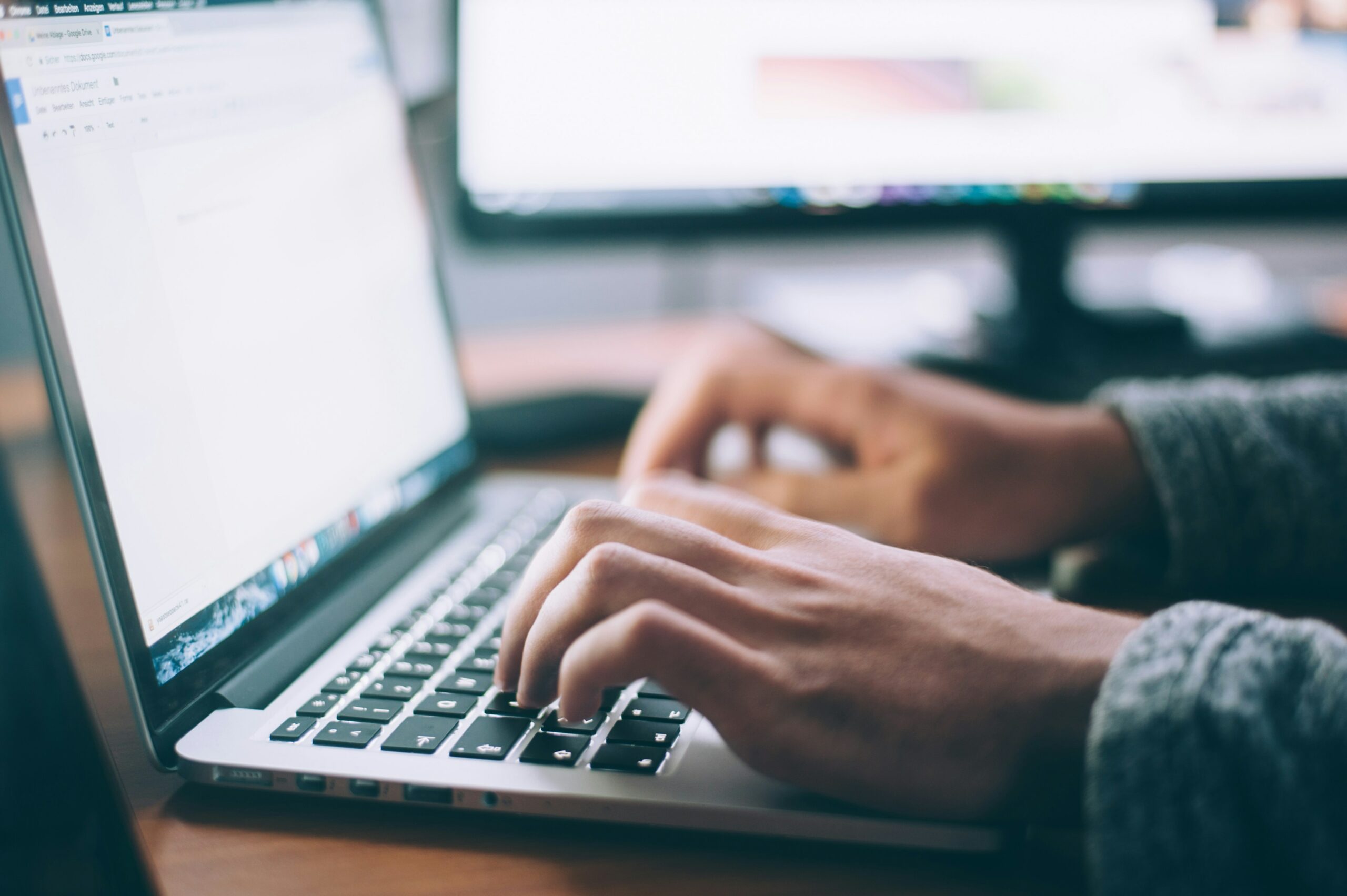 Hands typing on a laptop keyboard with a Google Doc open.