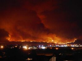A large orange fire covering the sky above a town.
