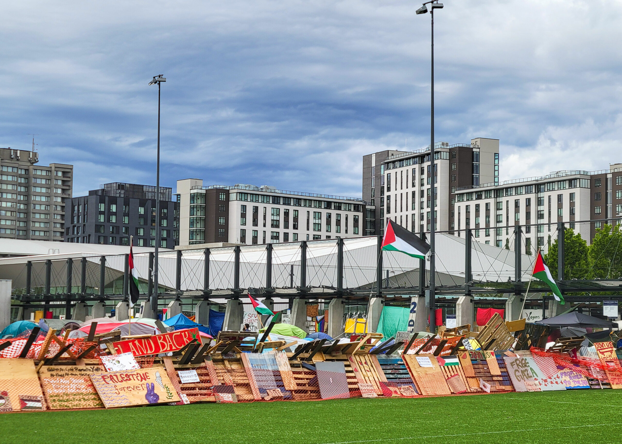 a barricaded encampment at UBC on the MacInnes field, with signs and flags in solidarity with Palestine