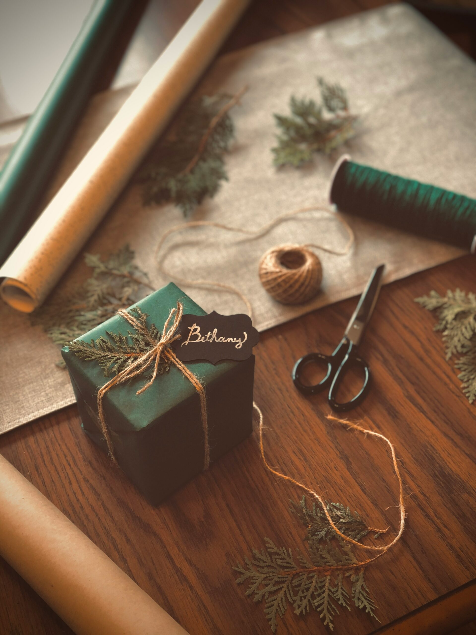 A gift box wrapped in green paper with a twine bow tie.