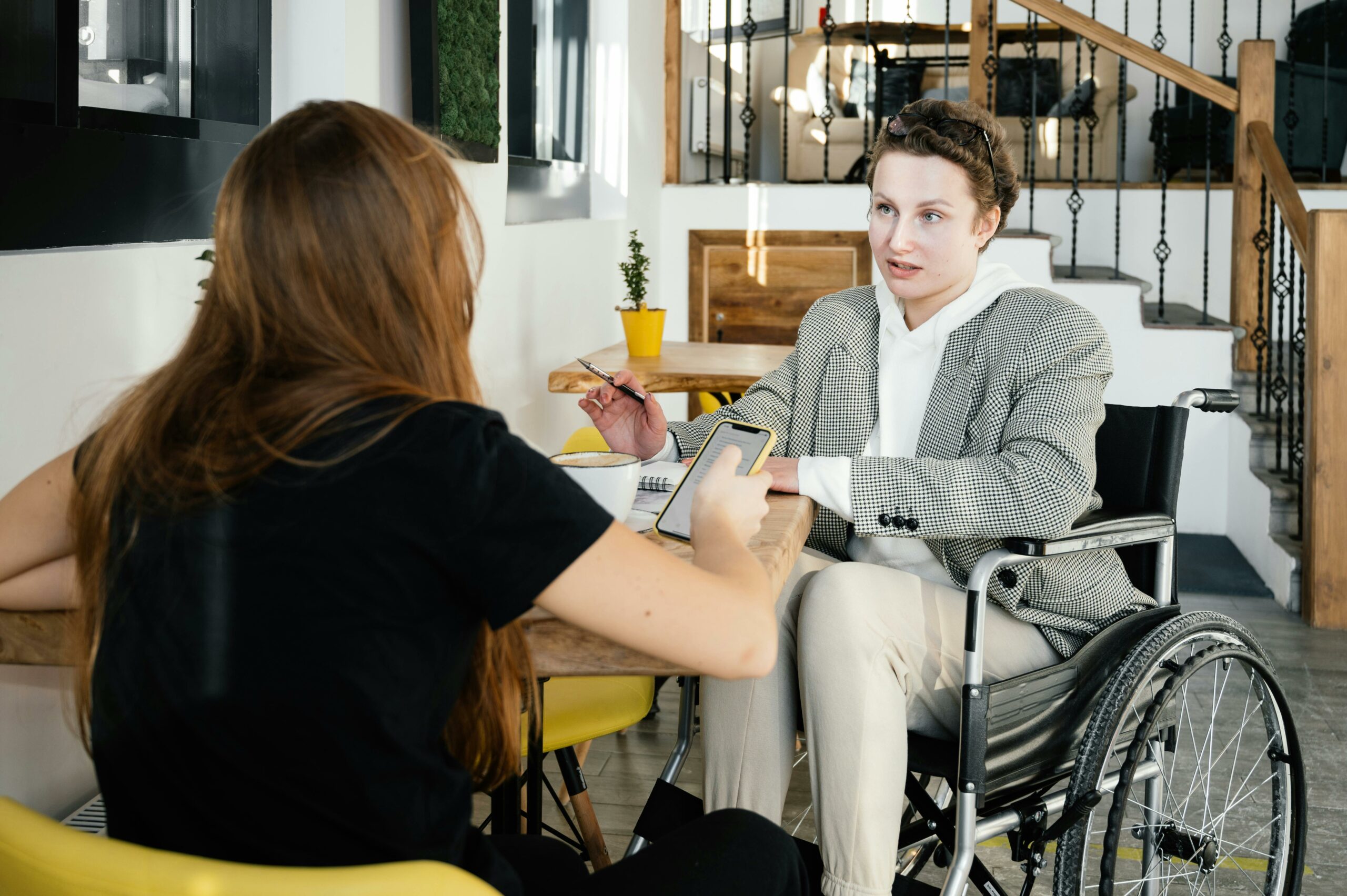 Person in wheelchair communicating with a colleague in the cafe