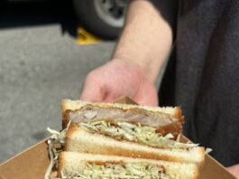 A sandwich with toasted white bread stuffed with sliced white cabbage and golden-brown fried pork cutlets.