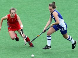 Two women competing for a goal in field hockey.