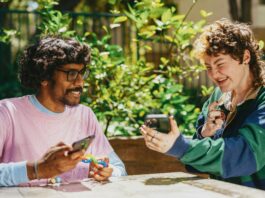 Two people laughing and looking at a phone.