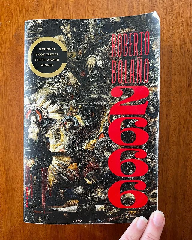 The cover of Bolaño’s 2666 (written on the cover in red), which features a renaissance-styled painting of a woman surrounded by faded hands and faces.