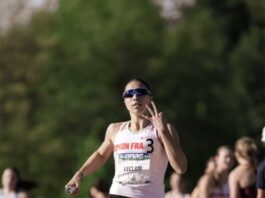 Sprinter Marie-Éloïse Leclair holdng up three fingers while running with a baton in her hand.