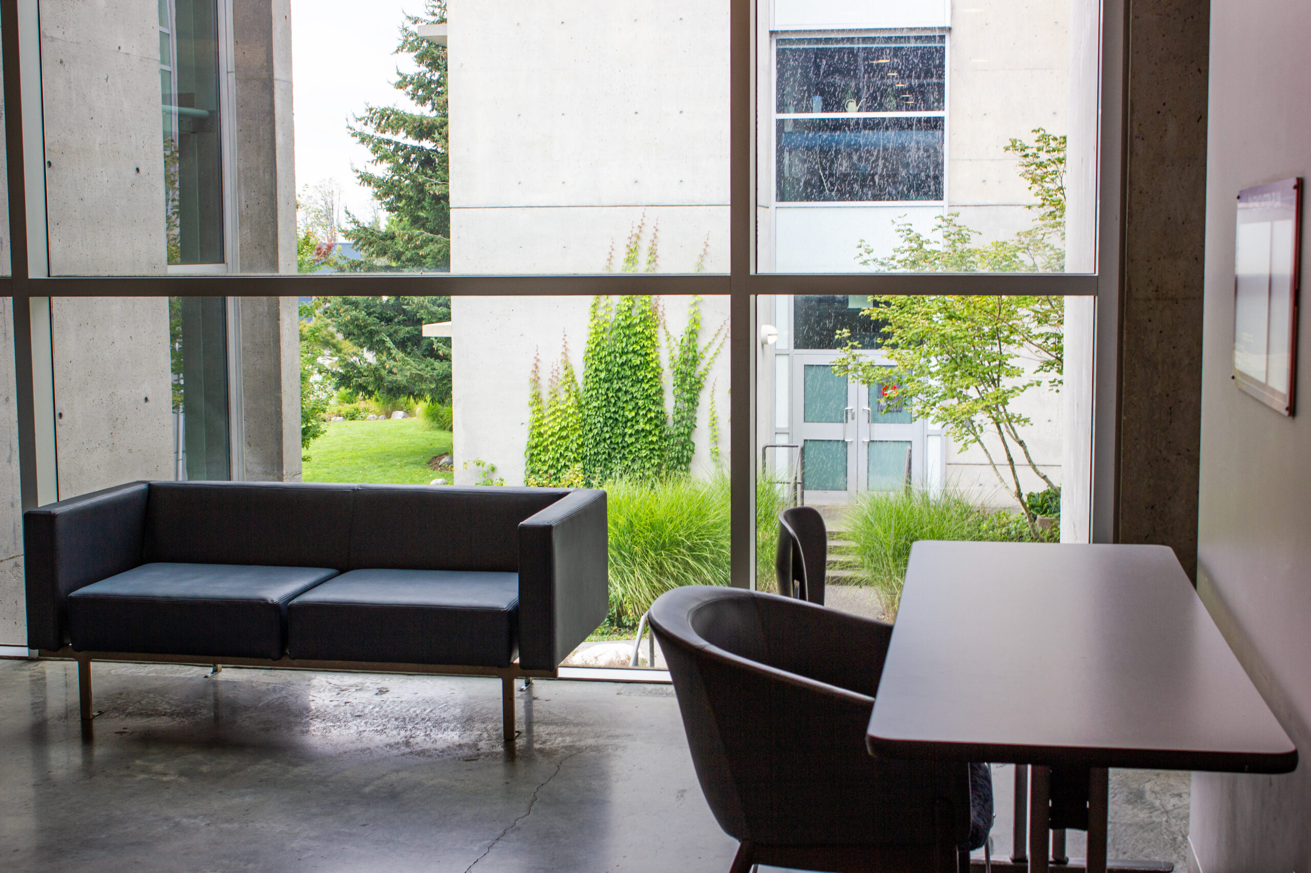 A small black couch and a chair with a desk in a quiet corner at SFU.