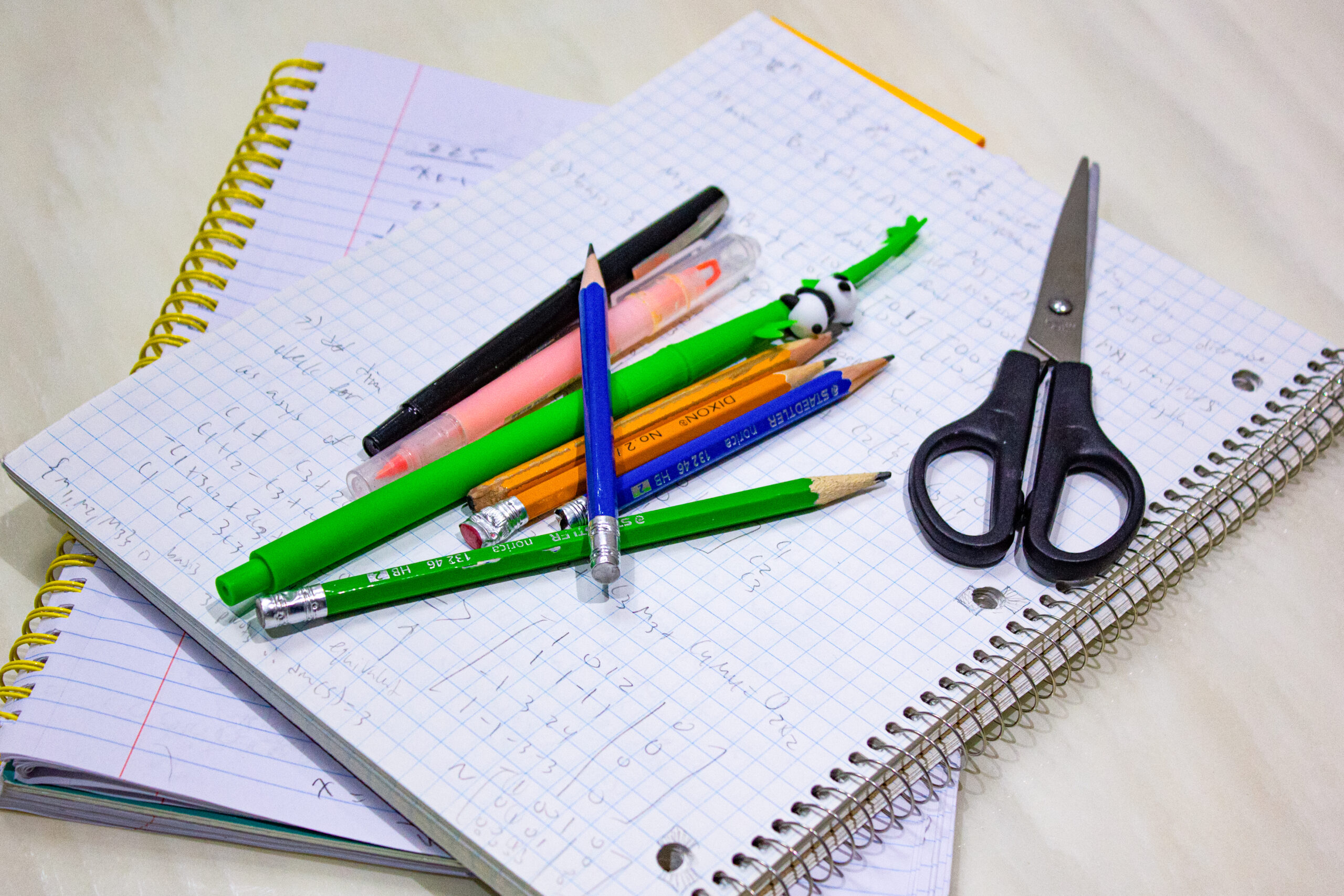 Notebooks with pens and scissors on top