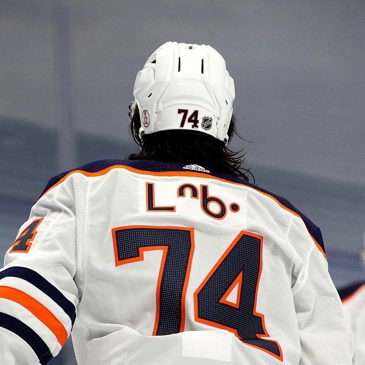 A hockey player skating away from the camera with his name plate written in Cree syllabics.