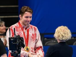 A man in a Canadian uniform tearfully shakes hands with a woman. Hanging from his shoulders is a gold medal.