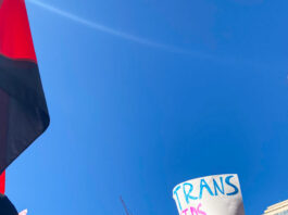 This is a photo of multiple pro-SOGI posters at a counter-protest in Vancouver. One reads, “TRANS KIDS EXIST.”