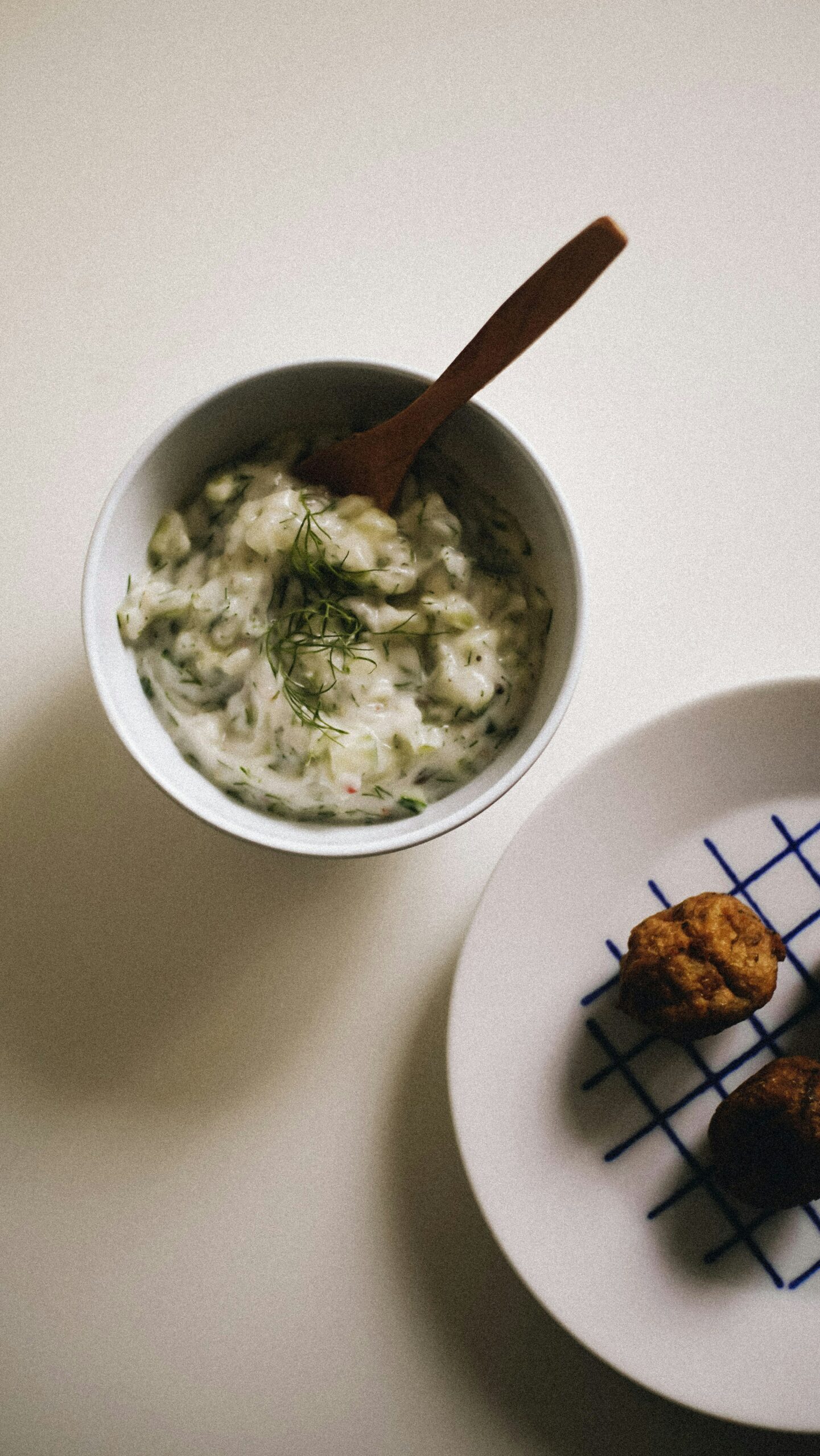 A bowl of creamy white tzatziki dusted in sprouts and green specks.